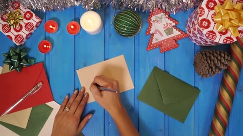 Woman Writing Merry Christmas Card at Festive Table