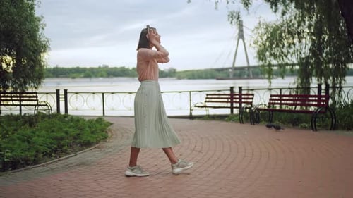 Female Holding Earphones Enjoy Walk in Summer Town