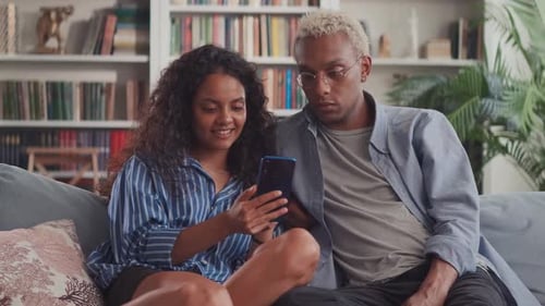 Couple Relaxing on Couch Looking at Smartphone