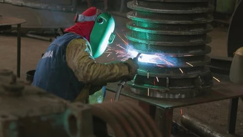 Metalworker Welding Metal Cylinder in Industrial Workplace