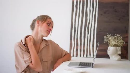 Young Woman Feels Tired Working on Laptop at Home Office