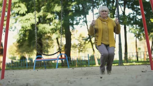 Lonely Sad Old Woman Riding on Swing in Park, No Friends and Family, Abandoned