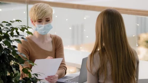 Women Discussing Paperwork at Desk in Office