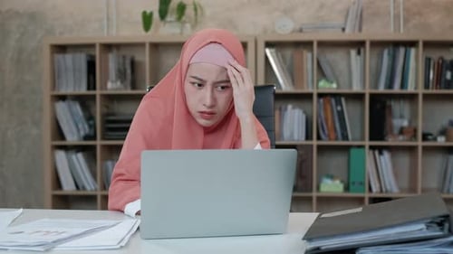 Muslim female worker feeling stressed and worried about online work.