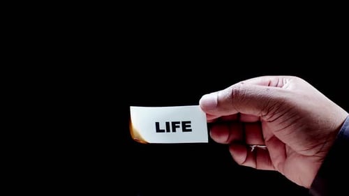Hand Burns Card with Word 'Life'