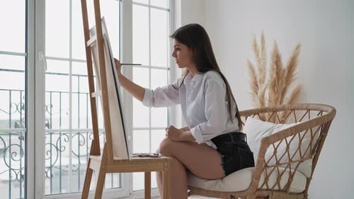 Young Woman Painting on Canvas in Sunny Room