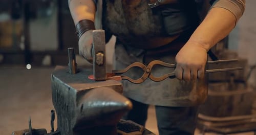 Blacksmith Shaping Hot Metal at Anvil with Hammer
