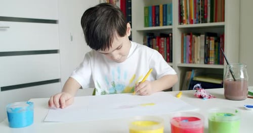 Child Drawing With Yellow Marker at Table