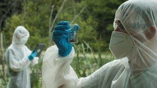 Scientists in Protective Suits Examining Samples in Nature