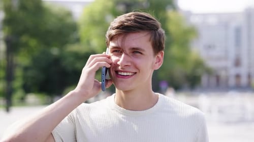 Happy Young Man Talking on Phone During City Walk
