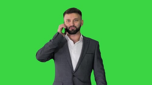 Businessman Walking and Talking on Mobile Phone on a Green Screen, Chroma Key.