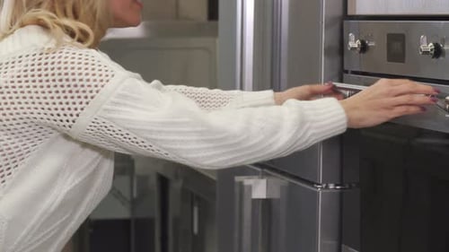 Woman Opens Oven in Modern Kitchen