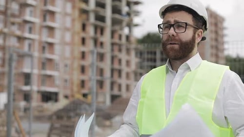 Architect Reviews Building Plans at Construction Site