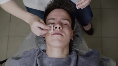 Top View of Beautician's Hands Clean Male Face with Cotton Pads During Procedure