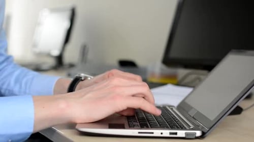 Young Handsome Man Works on Laptop (Notebook) in the Office - Closeup