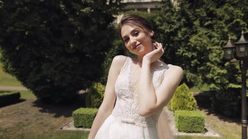 Beautiful and Lovely Bride in Wedding Dress and Veil in the Park Waiting for Groom