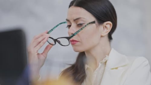 Woman Removing Glasses and Rubbing Eyes
