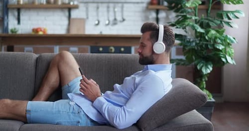Man Relaxing on Sofa with Phone and Headphones