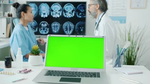 Chroma Key Green Screen Laptop with Doctor and Nurse in Uniform Discussing MRI Scans in Background