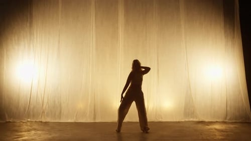Silhouette of a Professional Dancer Performing in Studio in Soft Warm Lighting