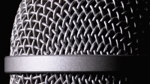 Le microphone pivote sur fond noir. La grille dynamique du microphone tourne en gros plan