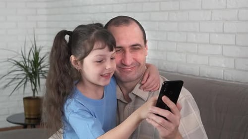 Smiling Father and Child Using Mobile Phone Together