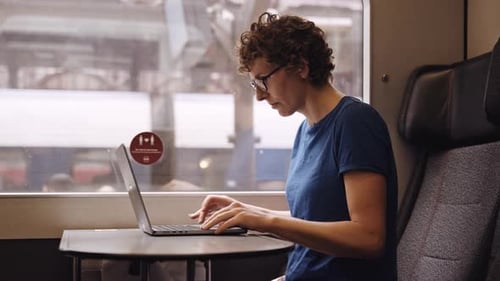 Woman Working on Laptop During Train Ride