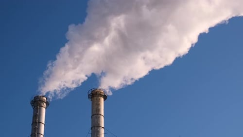 Pollution Billows from Industrial Smokestacks Against Blue Sky
