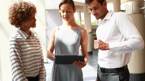 Coworkers Collaborate Using a Tablet in Modern Lobby