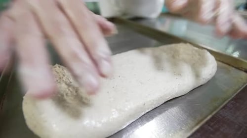 Baker Shaping Dough on a Metal Sheet