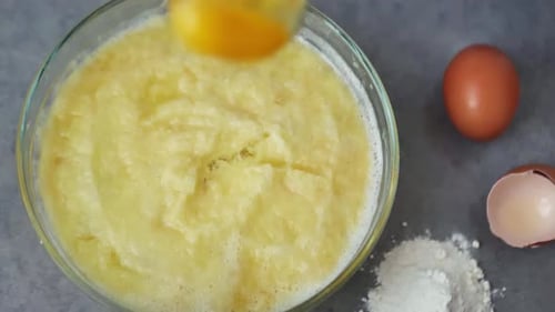 Close Up of Raw Egg Falling on Top of the Dough in Slow Motion
