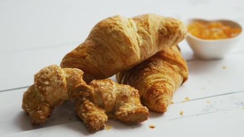 Flaky Golden Croissants with Marmalade on White Table