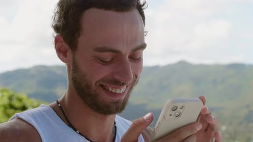 Smiling Man Using Smartphone Outdoors in Tropical Setting