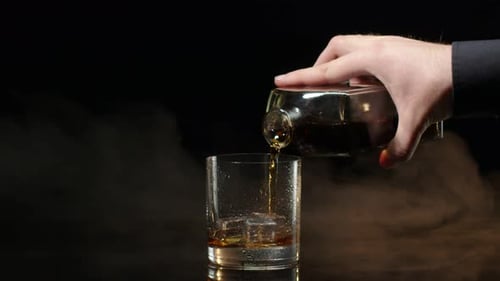 Liquor Poured into Glass with Ice Cubes