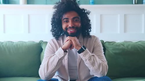 Jovem árabe estudante idade começa a sorrir senta-se no sofá na sala de estar em casa