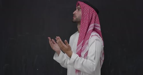 Young Adult Praying Indoors with Hands Raised