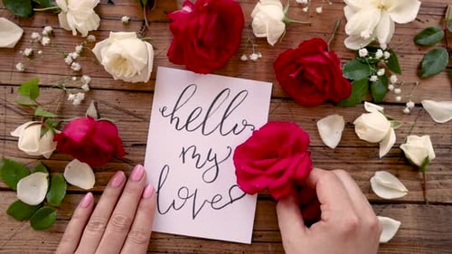 Mains avec une carte HELLO MY LOVE au-dessus d'une table en bois