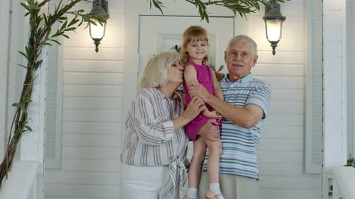 Grandparents and Child Standing Near Home