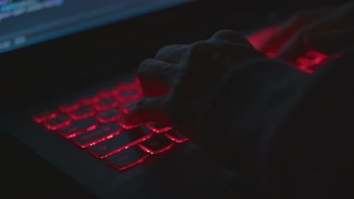 Hands Typing on Laptop with Red Backlit Keyboard