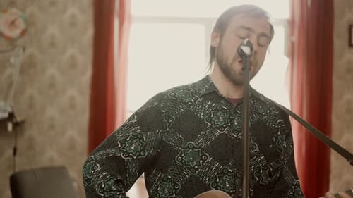 Man Singing and Playing Guitar in Living Room