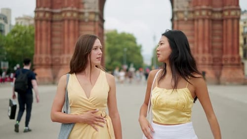 Two Young Women Walking and Talking in City
