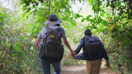 Young Asian man and Caucasian woman friend traveling walk with happiness in the forest together.