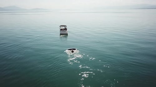 A wakeboarder is ready to start in the water, waiting for the boat to accelerate, aerial drone view,