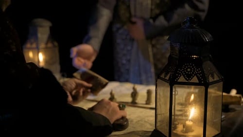 Man Examines Map by Candlelight in Dark Setting