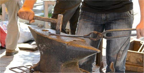 Blacksmith Forging Metal with Hammer on Anvil