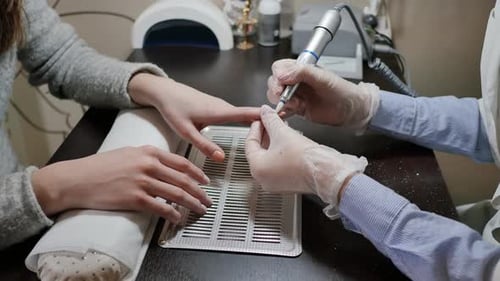 Manicurist Files Nail in Beauty Salon