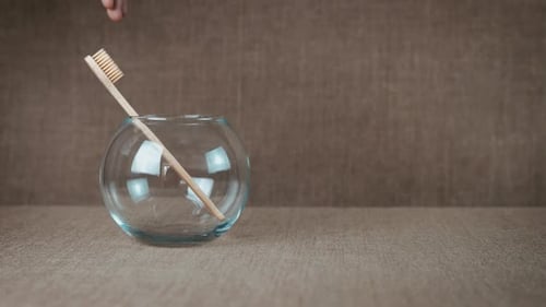 Wooden Toothbrushes in Glass Bowl on Woven Surface