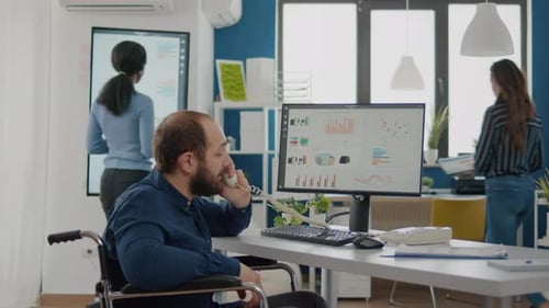 Man in Wheelchair Using Phone in Office