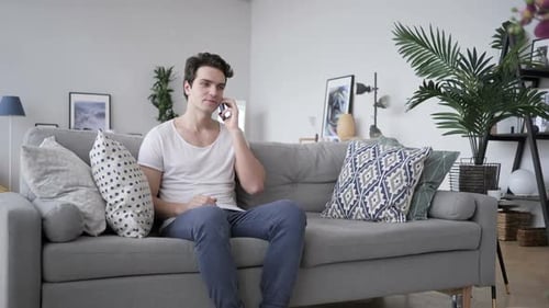 Man on Couch Answering Mobile Phone Call