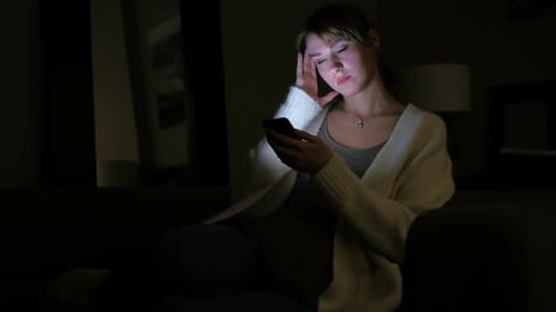 Woman Using Smartphone Indoors at Night